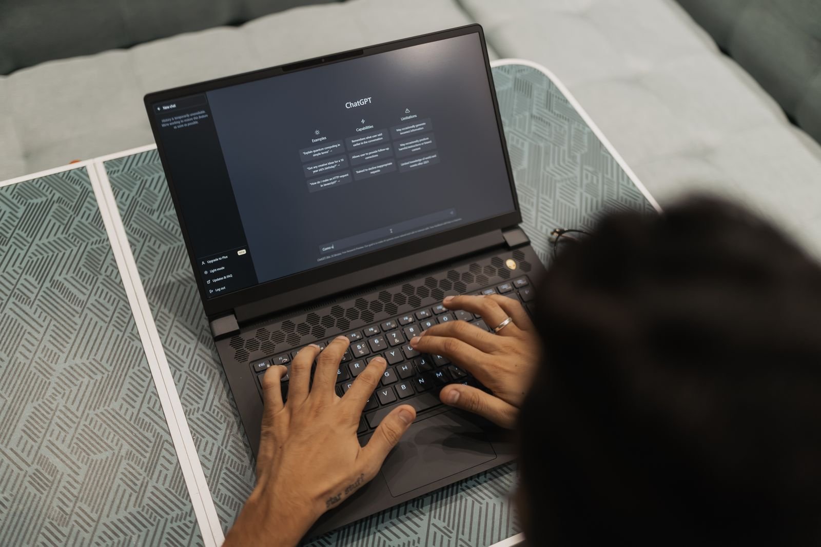 Hände tippen auf einem Laptop, auf dem die ChatGPT-Oberfläche geöffnet ist