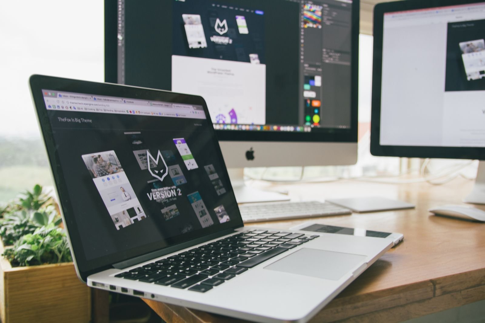 Laptop und Monitore mit Website-Design-Software auf einem modernen Schreibtisch