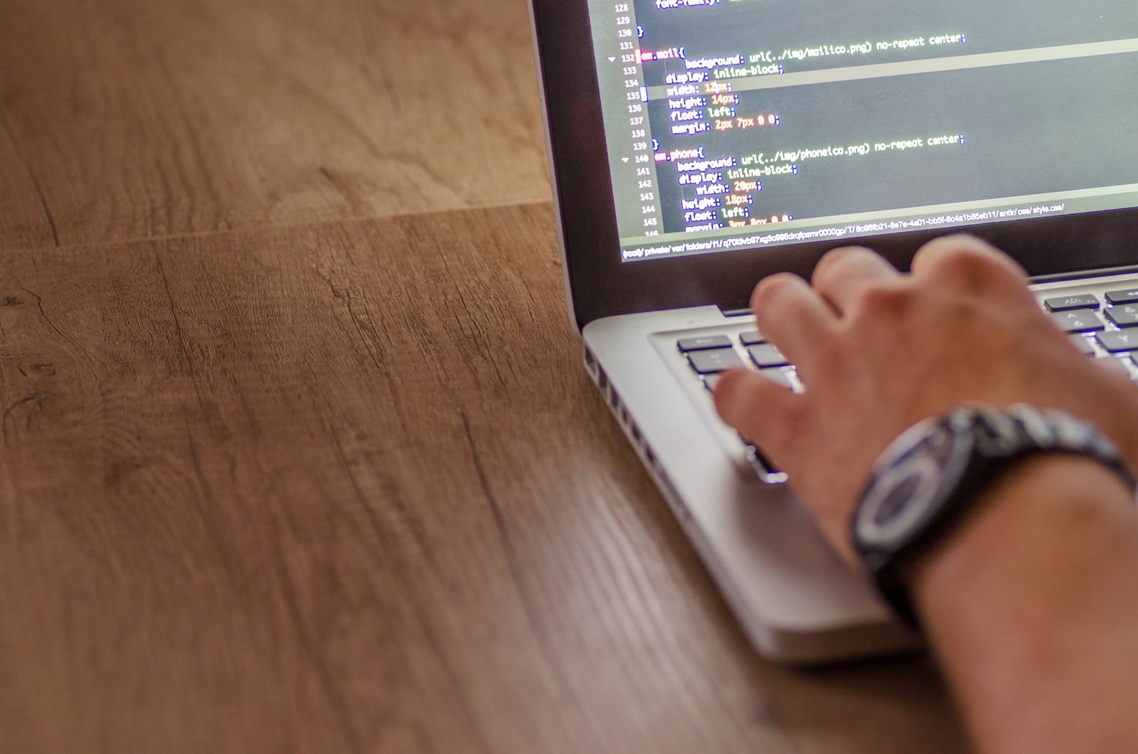 Nahaufnahme einer Person, die am Laptop Code für eine Website bearbeitet